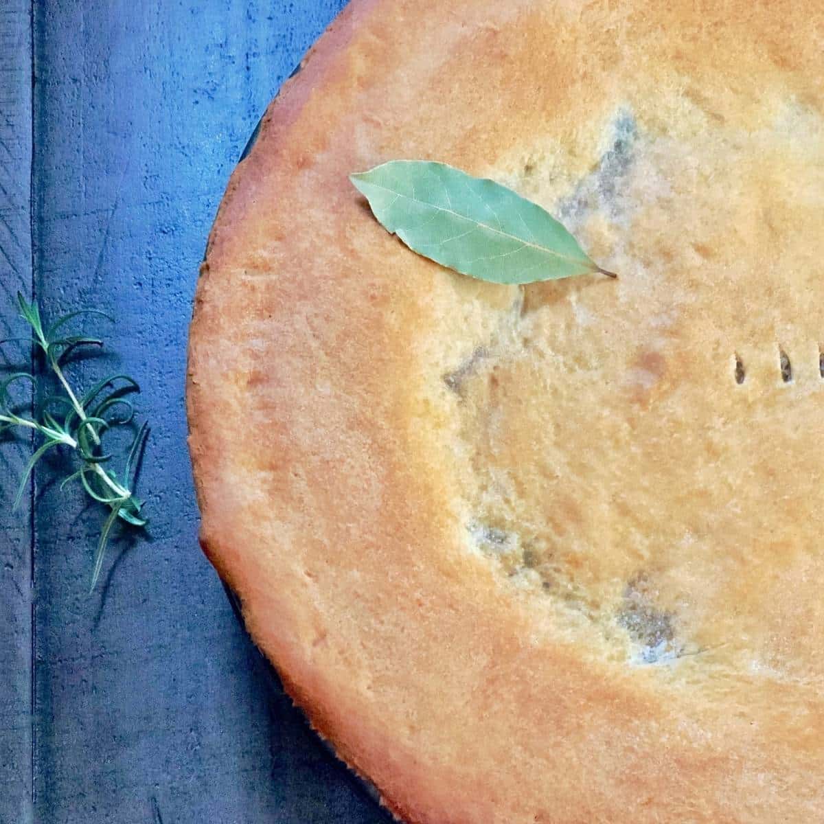 Top of pot pie crust garnished with a bay leaf and rosemary. 