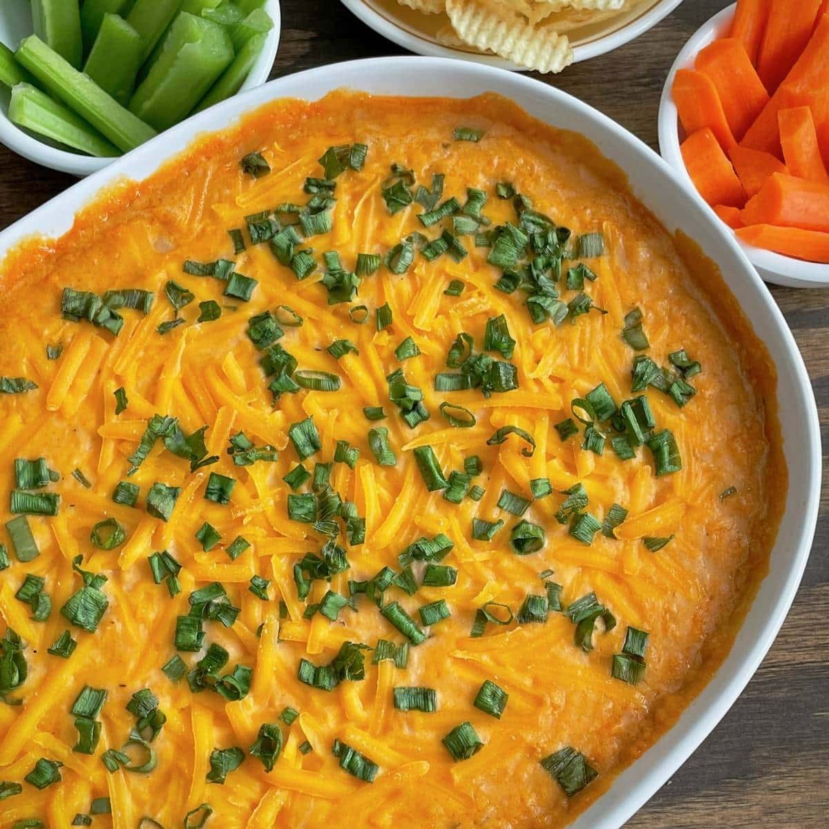 Vegan baked Buffalo dip with green onions as garnish on top.