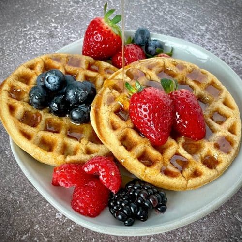 Vegan protein waffles with fresh fruit and syrup.