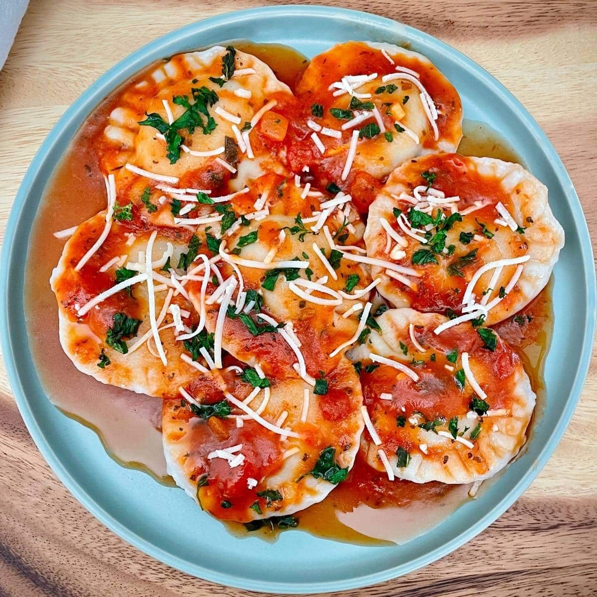 Blue plate with vegan ravioli and tomato sauce.