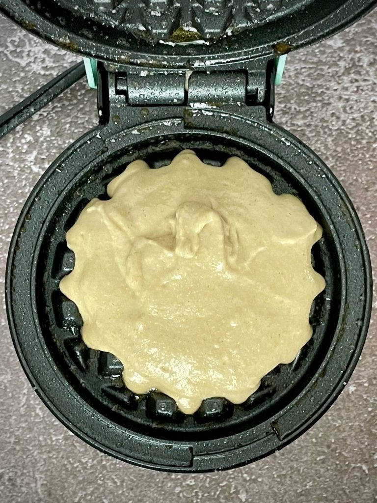 Waffle iron with raw batter on it.