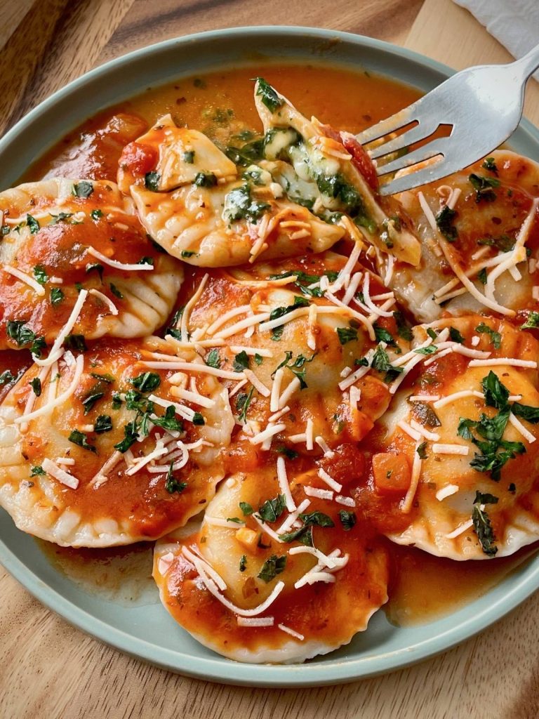 Ravioli on a plate with a fork holding one ravioli up.