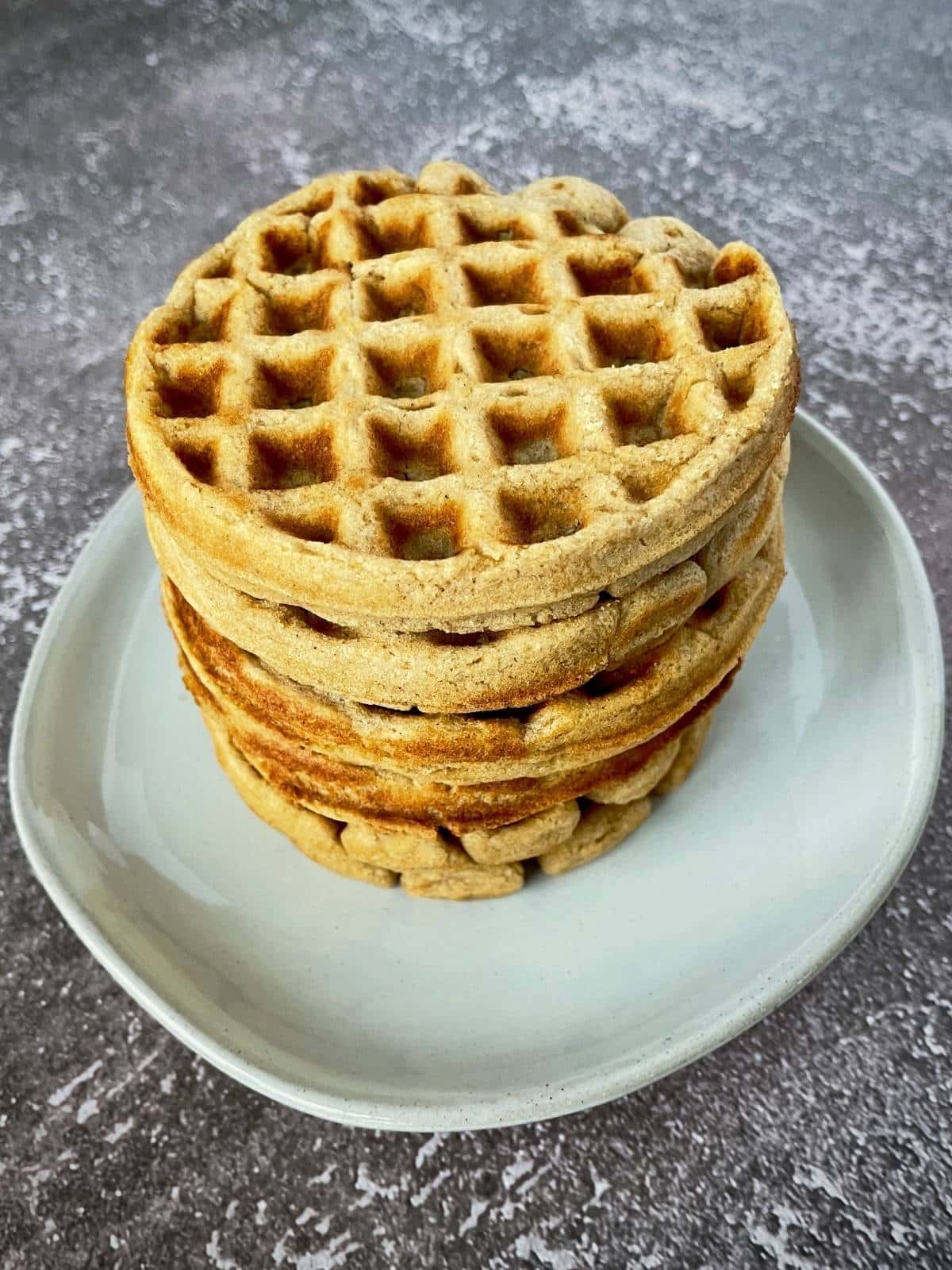 Stack of cooked waffles on a plate.