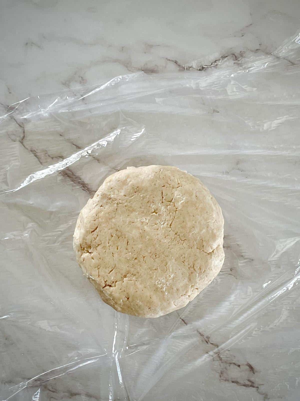 Pie dough disc in plastic wrap.