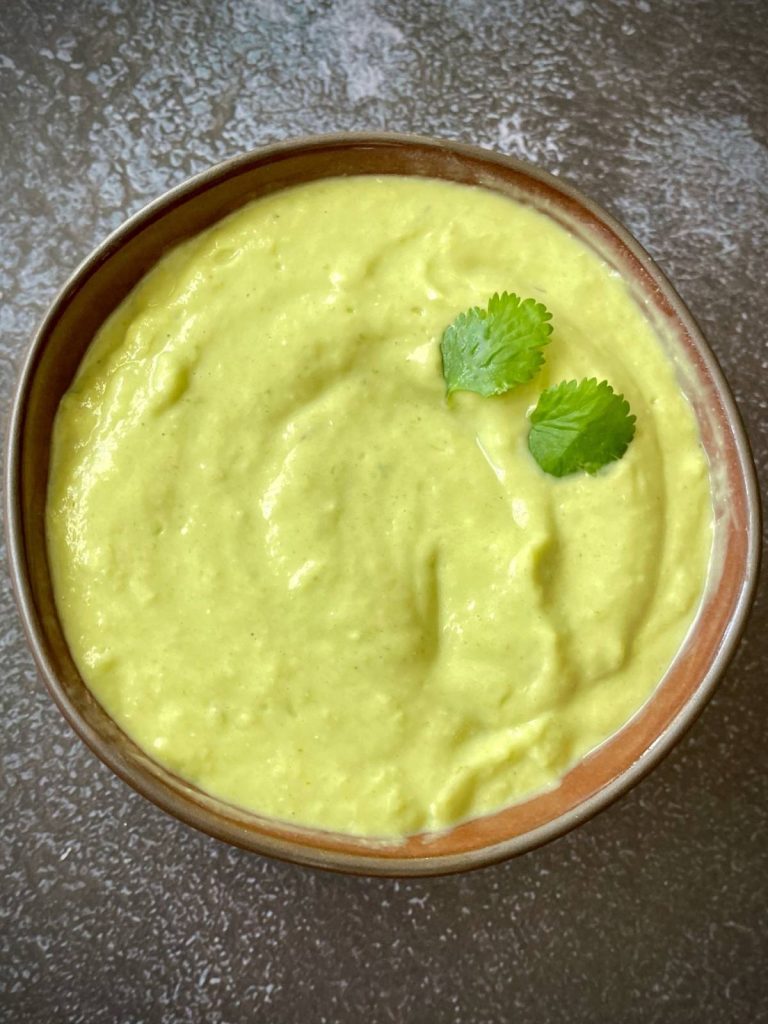 A bowl of vegan avocado crema, garnished with cilantro.