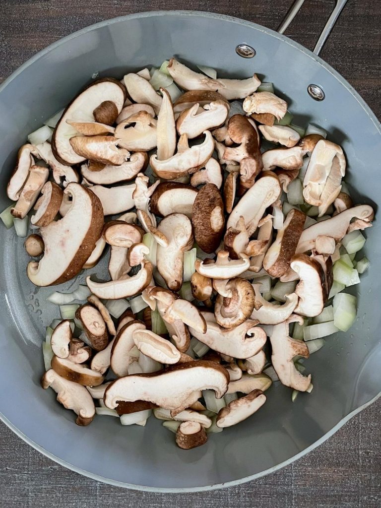 Shiitake mushrooms and sweet onions in a pan.