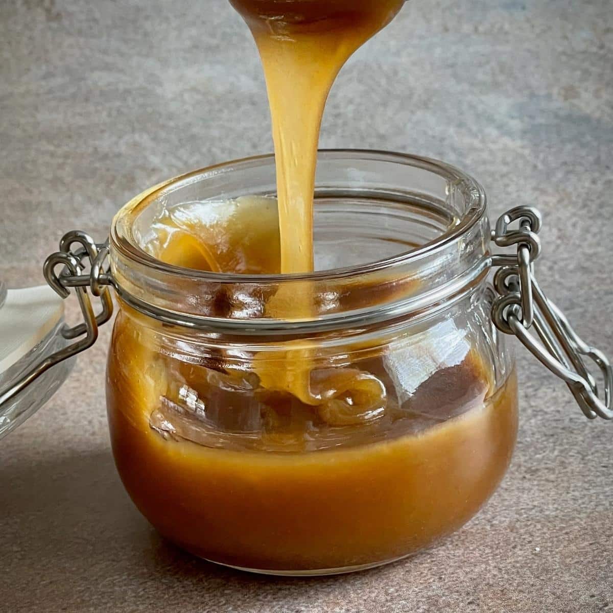 Vegan butterscotch sauce being poured into a jar.