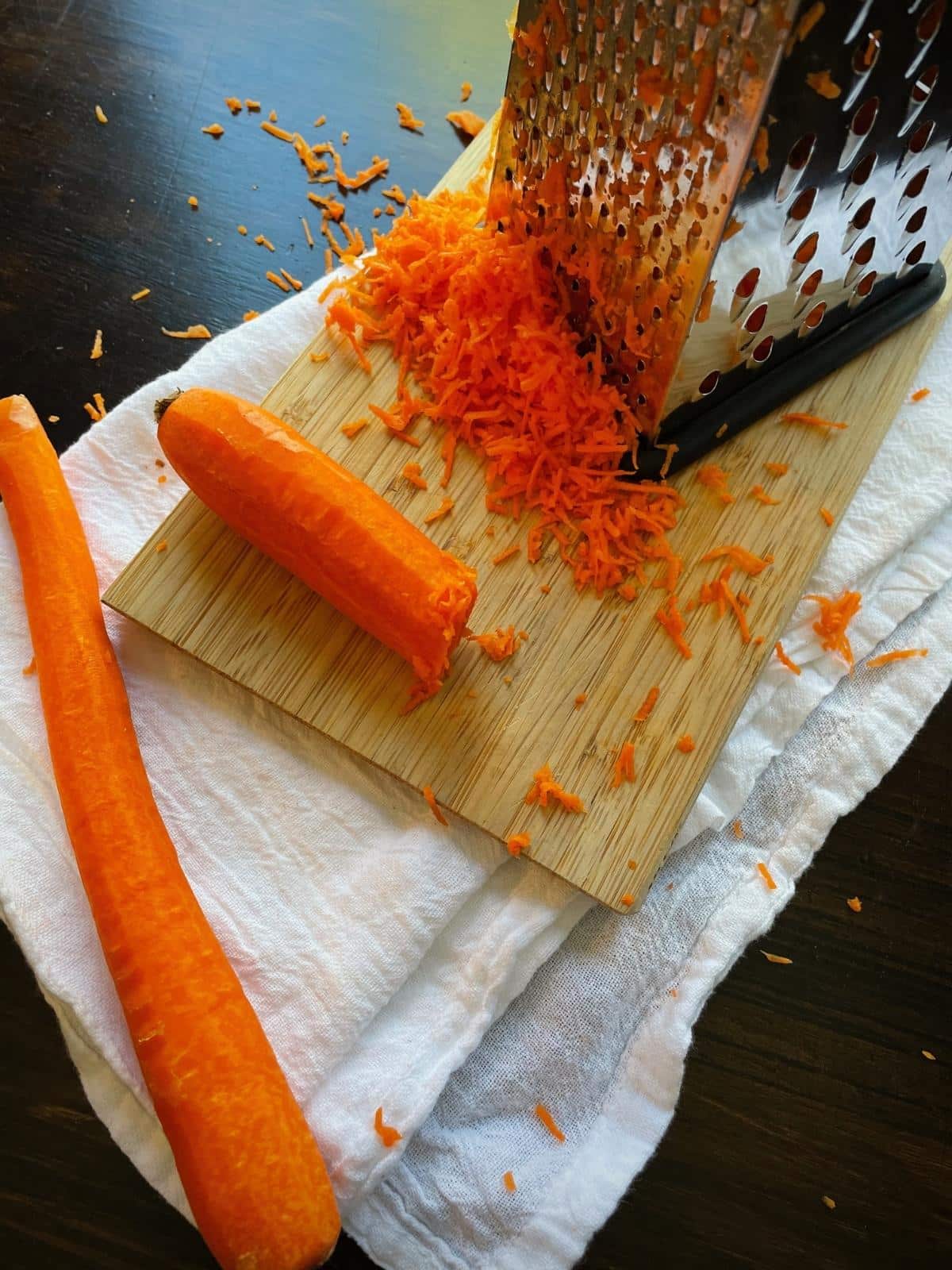 Grated carrots next to a box grater.