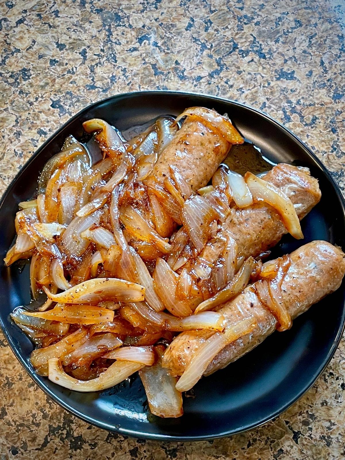 Brats and onions on a plate.