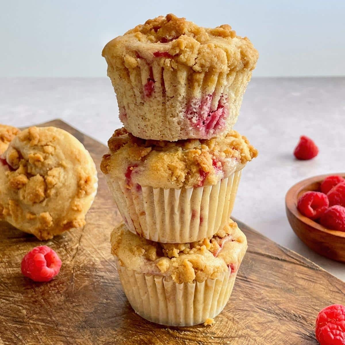 Three vegan raspberry muffins stacked on top of each other.