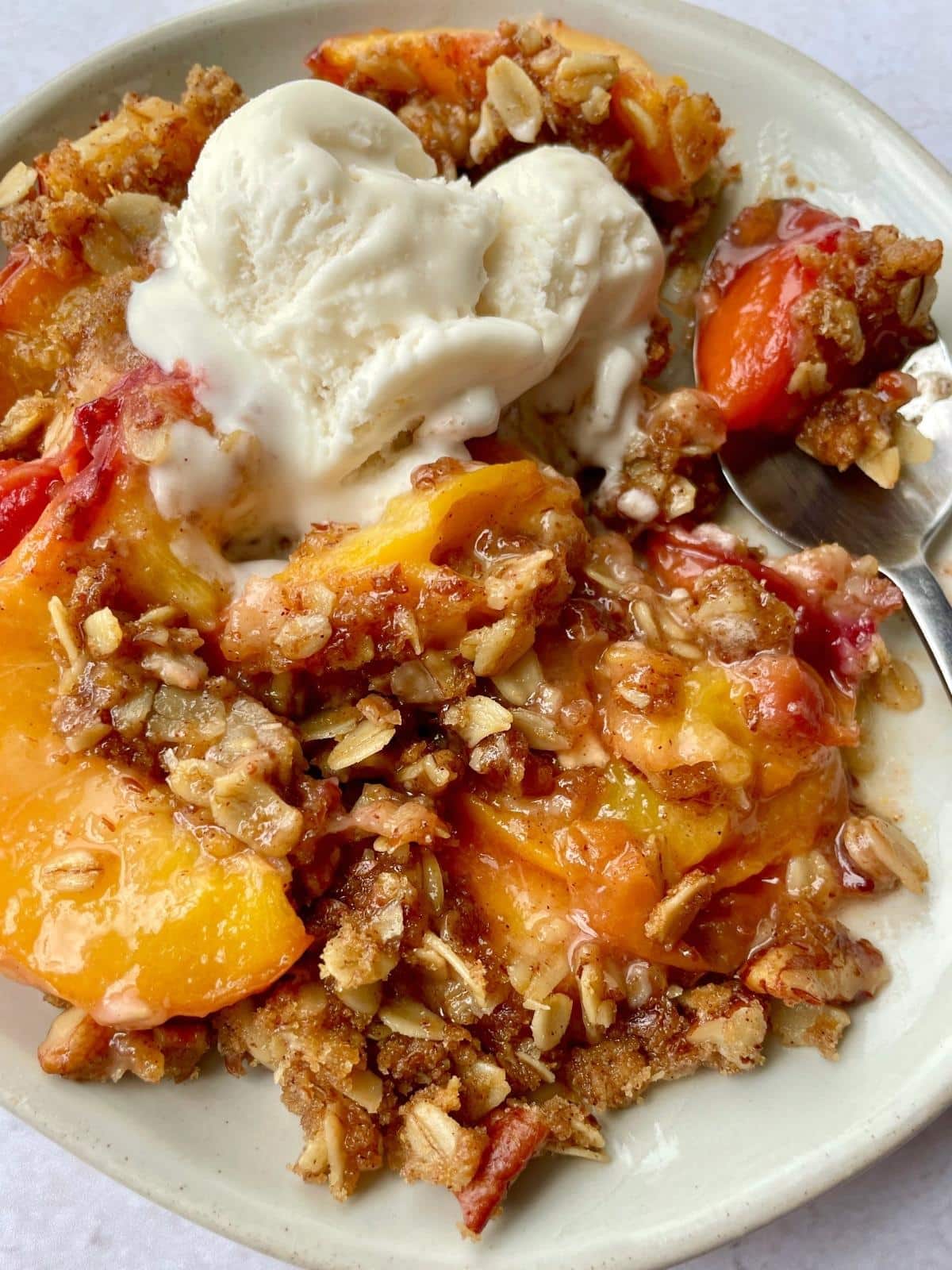 Eating peach crisp topped with ice cream.