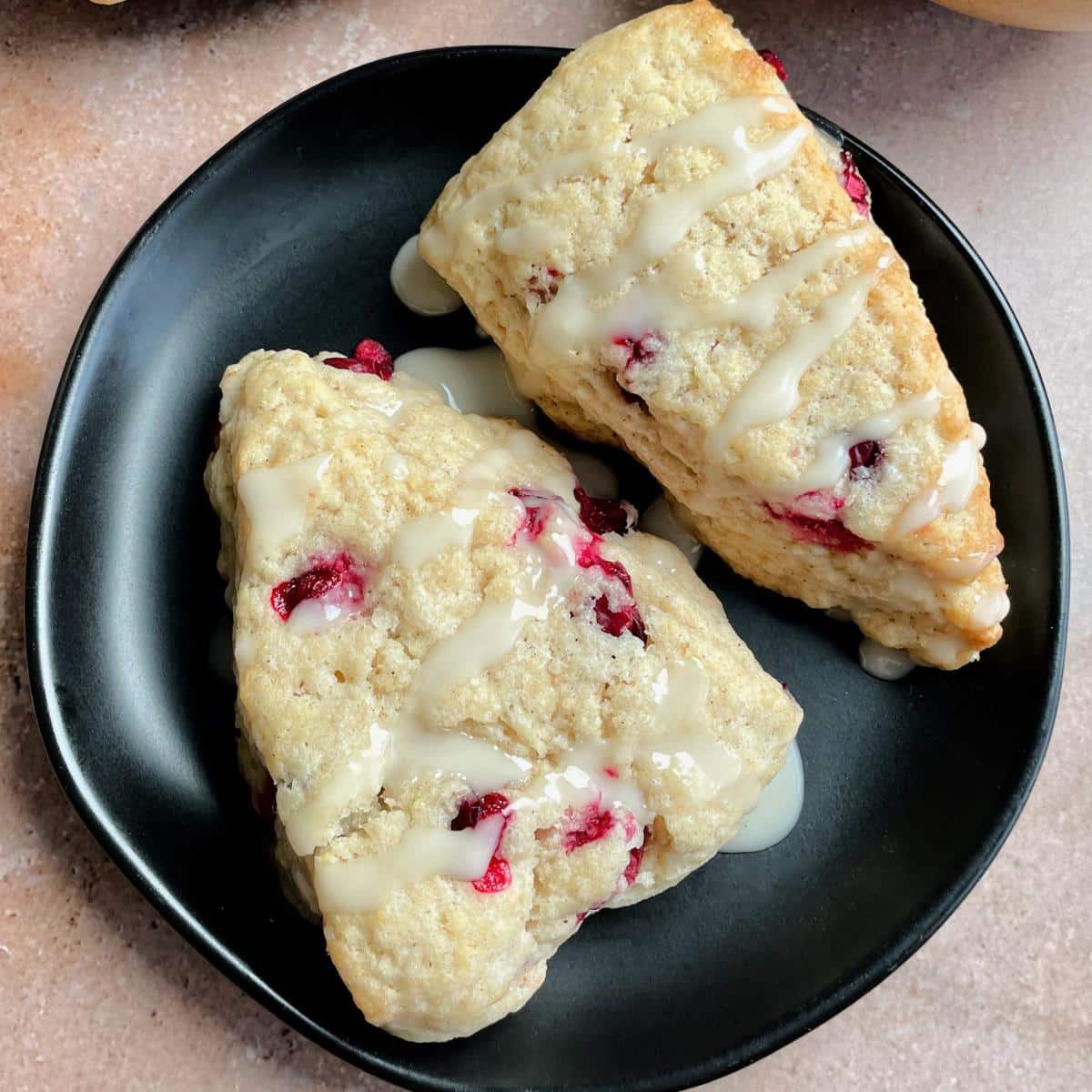 A plate with cranberry scones and almond glaze.