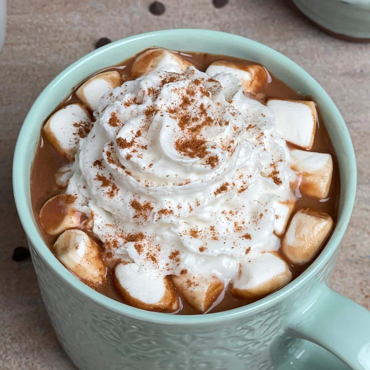 A mug with hot chocolate, whip cream, and marshmallows.