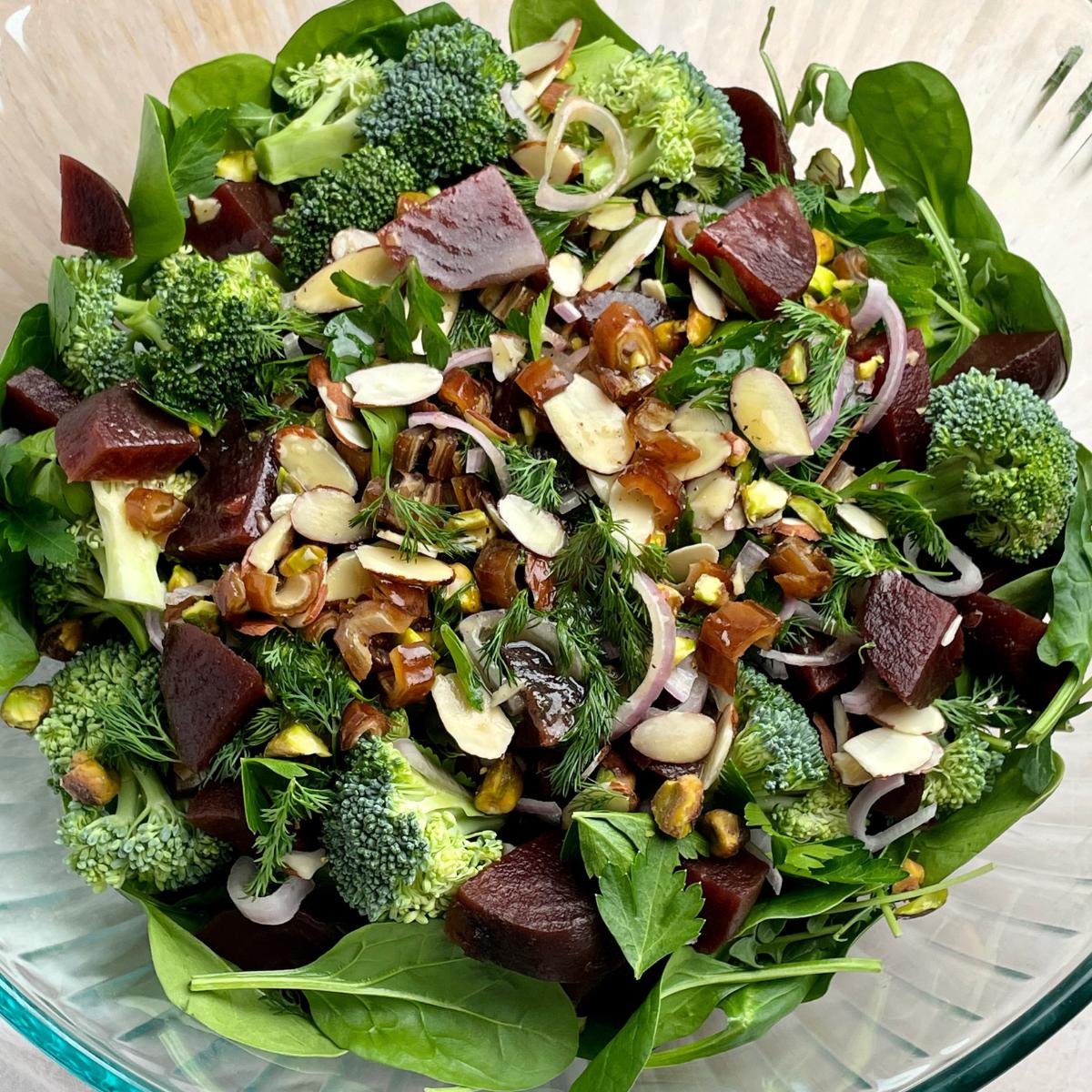 A bowl with broccoli beet salad and toppings.