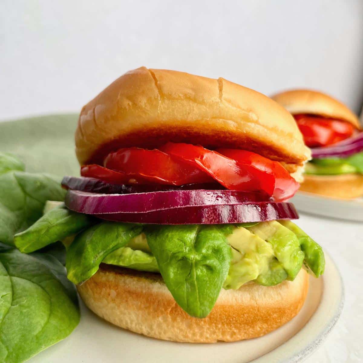 A roasted tomato sandwich with avocado, basil, and red onion.