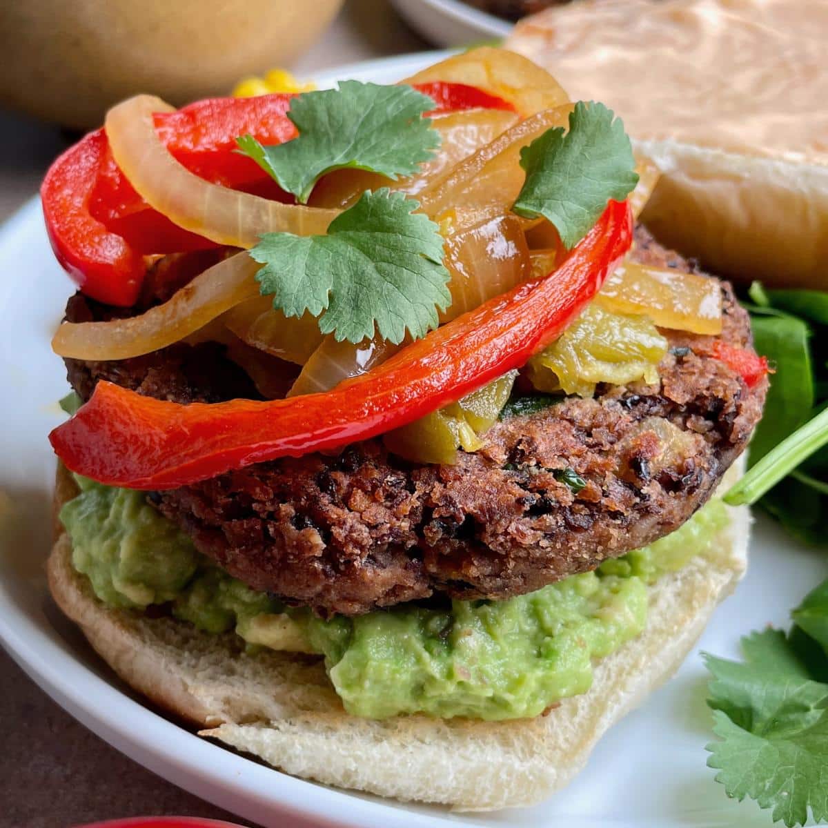 A black bean burger with peppers, onions, and avocado.