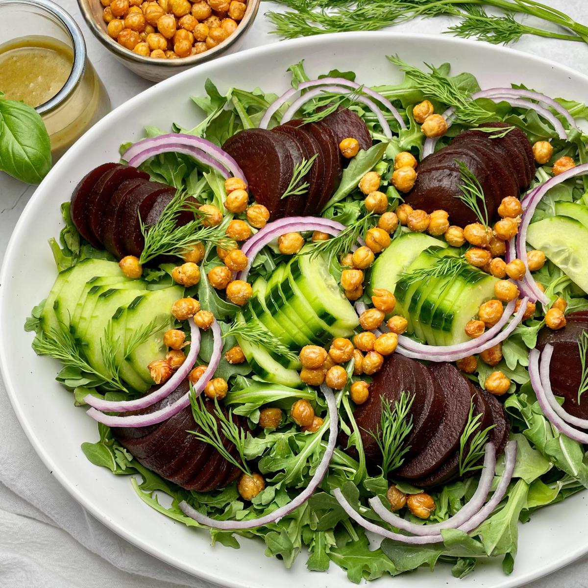 A tray with cucumber beet salad and a side of vinaigrette.