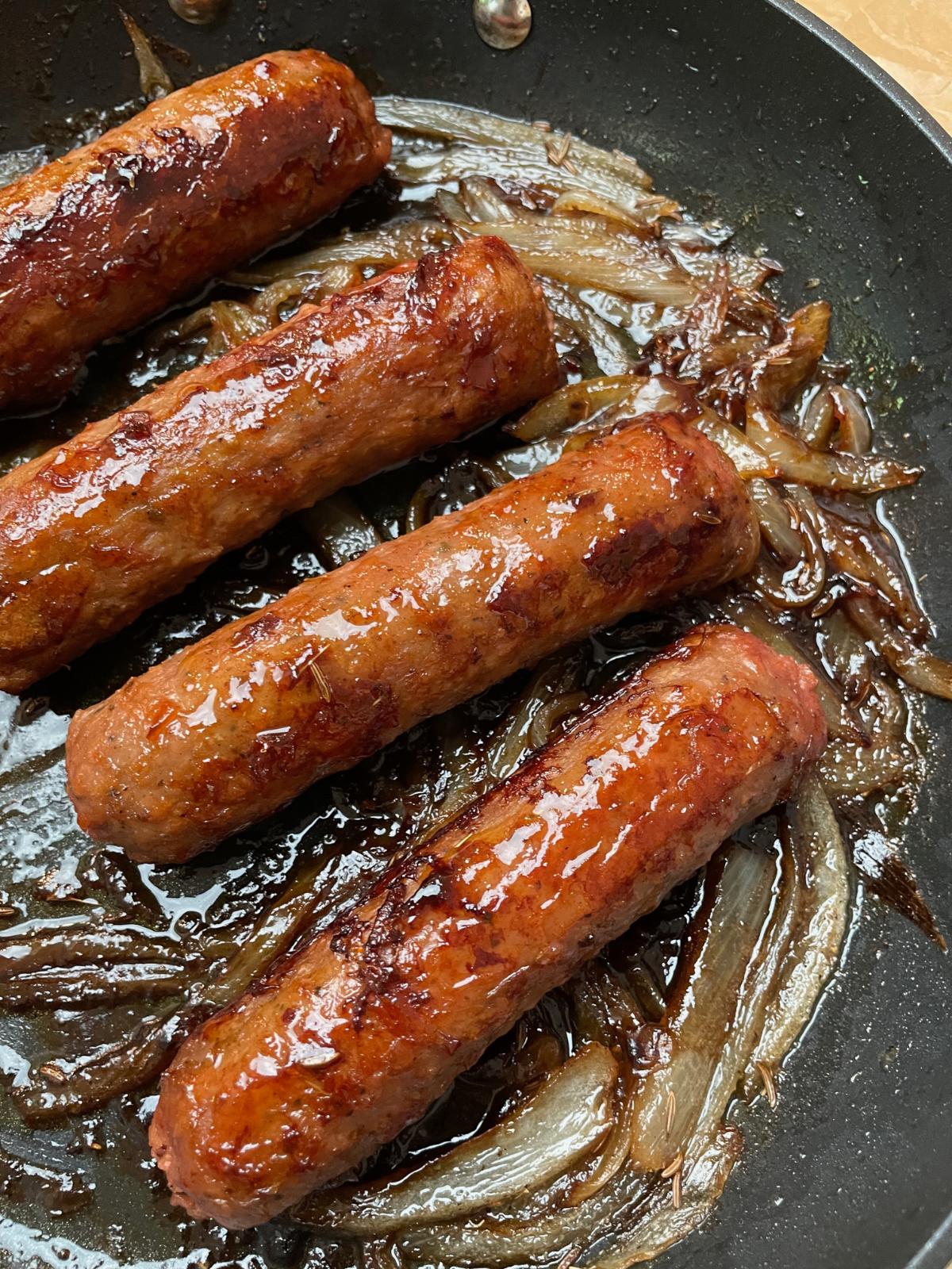 Plant based brats in a pan.