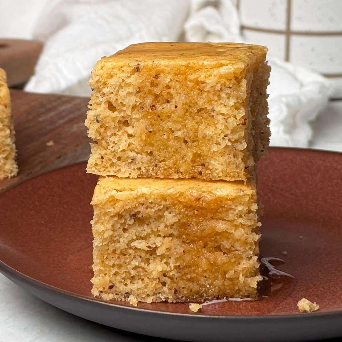 Two slices of cornbread stacked with agave syrup drizzled on top.
