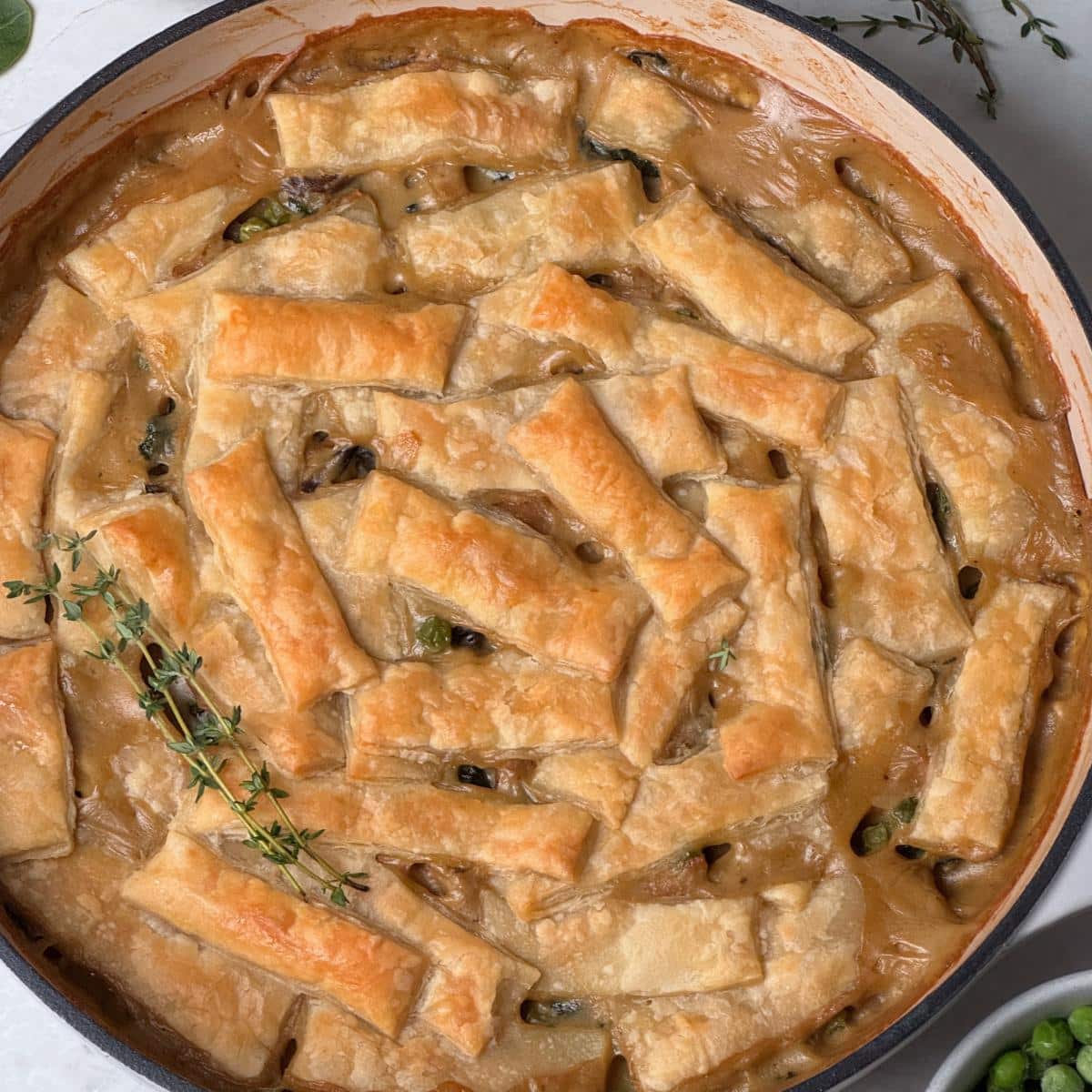 A vegan chicken and mushroom pot pie with puff pastry crust and fresh herbs.