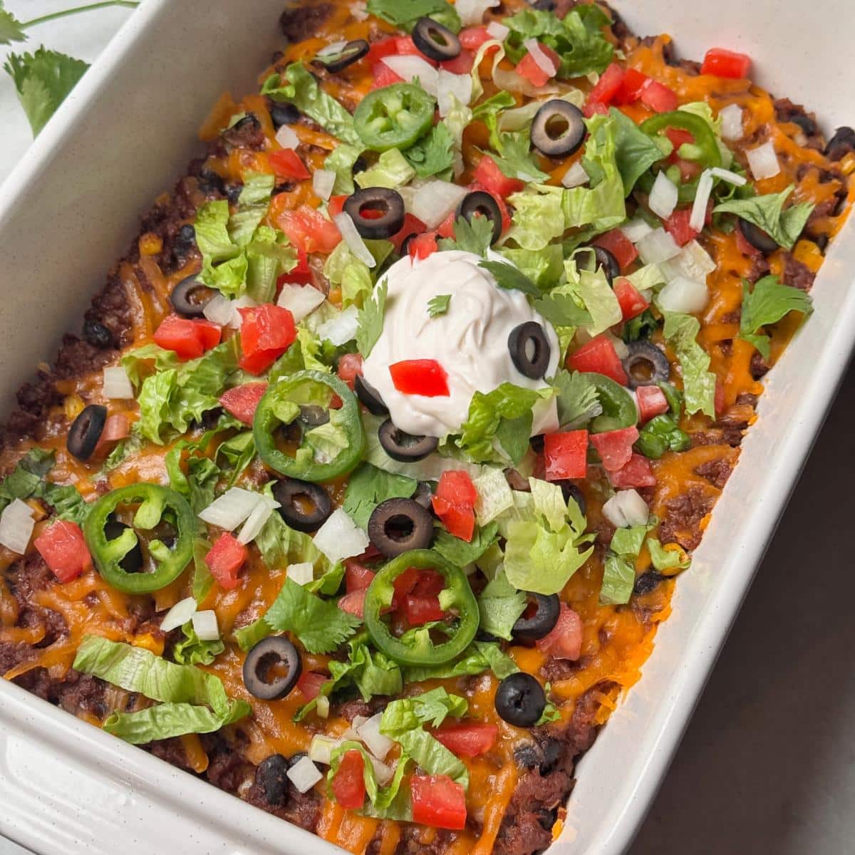 A picture of taco casserole with fresh vegetable toppings.