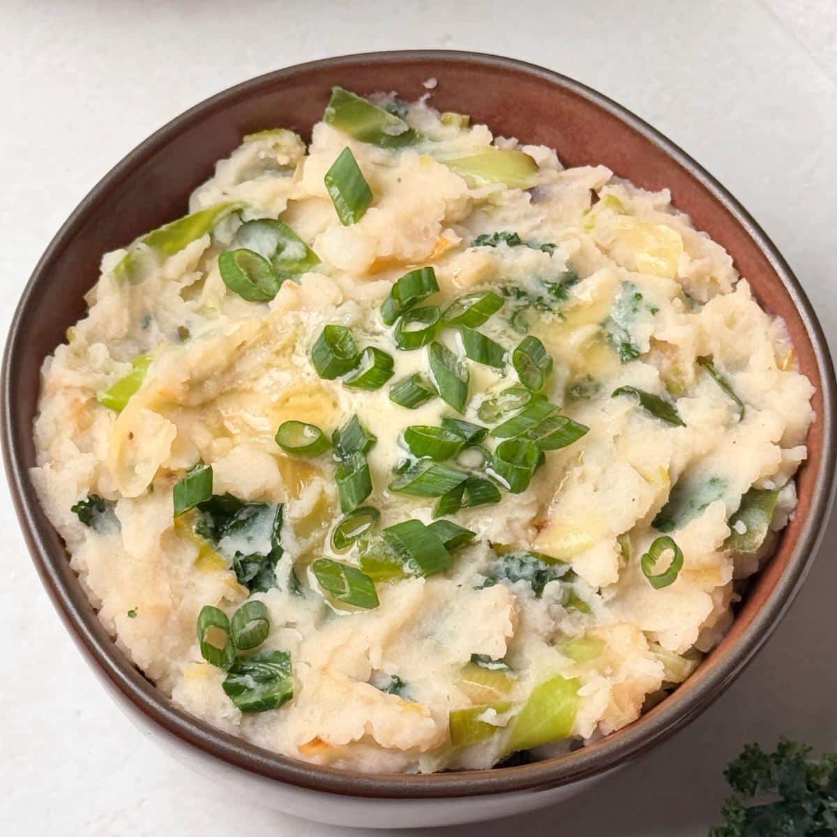 A bowl of vegan colcannon or Irish mashed potatoes with herbs on top.