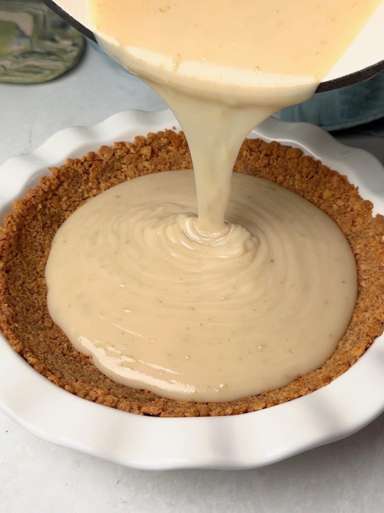 Pouring key lime filling into a pie crust.
